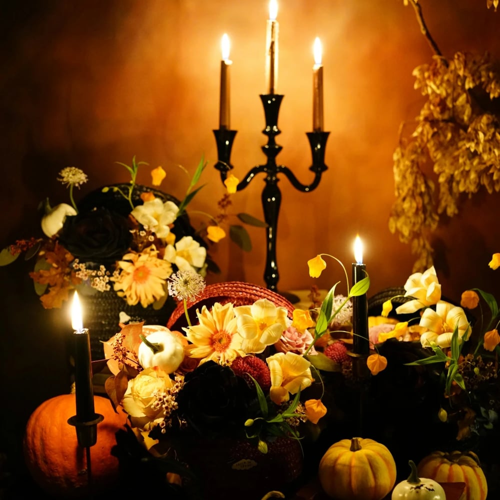 Orange pumpkins and Halloween flowers with candles on dark table